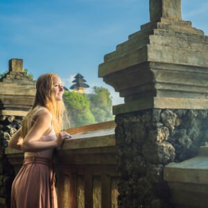 Young woman traveler in Pura Luhur Uluwatu temple, Bali, Indonesia. Amazing landscape - cliff with blue sky and sea.